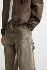 Pantalón color marrón con efecto lavado, corte relaxed fit, cinco bolsillos, aplicación de tira y bolsillo multifunción en perneras, cierre frontal con cremallera y botón.