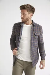 Sobrecamisa de viyela para hombre con estampado de cuadros en rojo y negro. Presenta cierre frontal con botones, bolsillos en el pecho con solapa y botón, y un interior capitoneado para mayor abrigo. Cuenta con un logo en grifa de cuero.