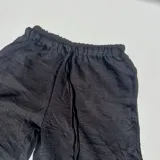 Pantalón negro de tiro alto, corte palazzo y cintura elastizada con cordón ajustable.