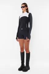 Top deportivo negro de tricot con recortes pisados con bordador, media polera, manga larga con mitones y estampa en lateral del frente y espalda.