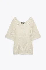 Top de crochet color crema, con cuello redondo y mangas cortas.