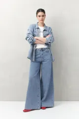 Pantalón de jean negro de calce ultra wide leg, tiro alto y silueta amplia desde la cadera hasta el bajo. Diseño clásico de cinco bolsillos y cierre con botón metálico y cremallera.