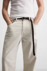 Pantalón de jean color beige, corte recto y relajado, con cintura ajustable con cordón interior, cinco bolsillos, efecto lavado y cierre frontal con cremallera y botón.
