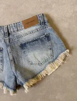 Short de jean celeste claro con cintura baja y flecos en el ruedo.