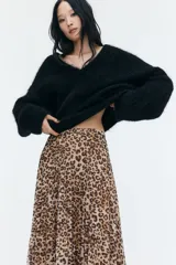 Pollera midi de malla plisada con estampado de leopardo, corte evasé, elástico en la cintura y forro de punto.