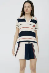 Remera polo tejida a rayas horizontales rojas y rosadas, con cuello clásico y bordado de ají verde.