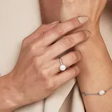 Anillo de plata 925 con perla de río central y circonias engarzadas en la alianza.