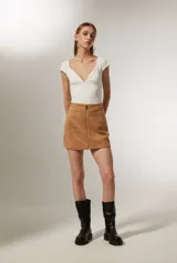 Minifalda color marrón de poliéster con cierre frontal de cremallera y apliques de tachas metálicas formando estrellas. 