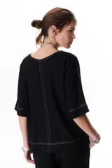 Blusa de lino color beige claro, con mangas 3/4 y cuello redondo. Presenta pespuntes a contratono en el centro, puños y ruedo.