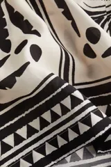 Pantalón de tiro alto con elástico revestido y cordón para ajustar fino en la cintura. Piernas amplias de corte holgado con estampado de flores y figuras geométricas en blanco y negro.