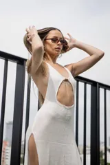 Vestido largo de tejido liviano color blanco, con escote halter, recorte en el abdomen, espalda descubierta y aberturas laterales.