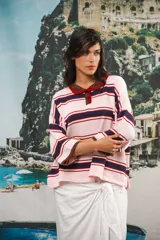 Remera de algodón y poliéster a rayas horizontales rojas y azul marino sobre fondo crudo. Tiene cuello tipo polo con botones, mangas amplias y corte oversized.