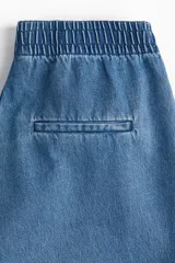 Pantalón culotte de denim azul claro, con cintura elástica fruncida, bolsillos laterales y corte holgado.