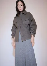 Chaqueta bouclé color gris con cuello camisero, cierre frontal con botones, dos bolsillos con solapa y manga larga.