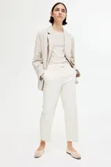 Pantalón cigarette tobillero color blanco, con cintura estándar, cierre y pretina prolongada con corchete oculto. Piernas ajustadas con abertura corta en los bajos, bolsillos al bies y bolsillo de atrás decorativo. Pliegues adelante y atrás.