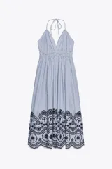 Vestido midi a rayas verticales azules y blancas, con escote en V, tirantes finos y cintura elástica. Presenta bordados florales calados en el ruedo.