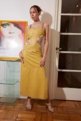 Vestido midi de cuero color maíz con cortes laterales y detalles dorados. Presenta tiras finas con pasamanería fucsia.