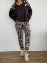 Pantalón de mujer con estampado animal print en tonos grises y marrones, con cintura elástica y cordón ajustable. El diseño es de corte recto y los puños están doblados.