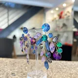 Aros colgantes hechos a mano con cristales Swarovski en tonos verde, lila y violeta.