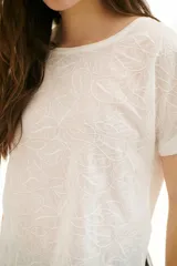 Blusa blanca con estampado de hojas en relieve, cuello redondo y mangas cortas.