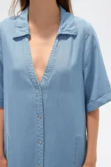 Vestido largo camisero de lyocell azul denim, corte holgado, con cuello camisero, mangas cortas con dobladillo y cierre frontal con botones.