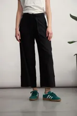 Pantalón negro de corte ancho, largo midi y cintura alta con lazo.