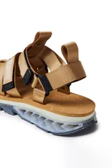 Sandalias con tiras de tela color beige, suela gruesa con detalles geométricos y ajuste con velcro.