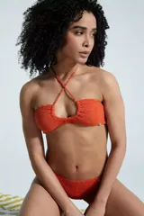 Top de bikini entero color naranja, con tiras para atar cruzadas al cuello, formando una abertura adelante.