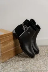 Bota clásica de cuero negro, baja, con detalles en metal y diseño cómodo para uso prolongado.