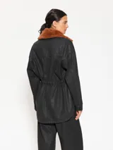 Parka negra de gabardina con cuello desmontable de peluche color marrón, bolsillos delanteros y cintura ajustable.