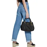 Bolso satchel negro de cuero sintético texturizado, con doble asa de mano y correa bandolera ajustable. Tiene cierre superior con cremallera, interior forrado y herrajes dorados. El frente presenta el logo triangular metálico de Guess y un dije colgante con el logo de la marca.