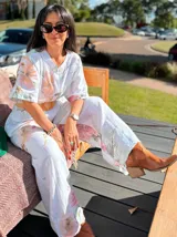 Pantalón palazzo verde claro con estampado de flores rosas, cintura elástica y lazo ajustable.