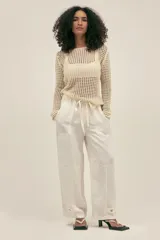 Pantalón color crema de lino y tencel, con bolsillos laterales, cintura elástica y cordón ajustable. Detalle regulable en el tobillo.