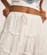 Minifalda blanca de viscosa con elástico y lazo en la cintura, recortes volados y rayas verticales en hilos metalizados.