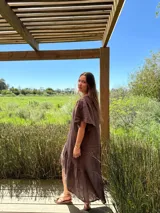 Vestido largo color beige, de corte amplio, con mangas cortas abullonadas y volado en el ruedo.