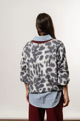 Buzo con estampado animal print en tonos grises y blancos, con cuello en V y puños en color bordó.