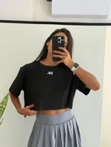 Remera negra de algodón con corte cropped y mangas cortas. Presenta un pequeño logo blanco invertido en el centro del pecho.