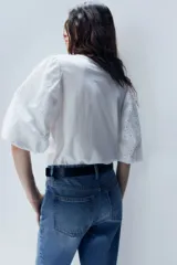 Top blanco de algodón con cuello redondo y mangas globo cortas de algodón bordado con forro de punto y ribete elástico.