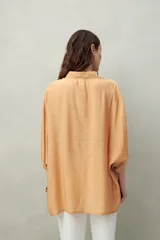 Camisa celeste de calce relajado con cuello clásico, mangas tres cuartos amplias y botones nacarados.