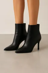 Botas de cuero sintético negro con punta fina y tacón de aguja.