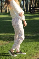 Pantalón de jogging blanco con estampado floral en tonos rosados, corte holgado y puños elásticos.