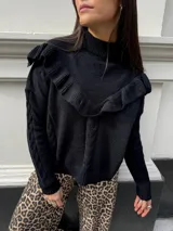 Sweater negro de punto con cuello alto y volados en el pecho.