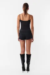 Short de jean negro con roturas, tiro medio, cintura con pasacintos, cierre y botón metálico.