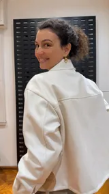 Campera color crema de algodón forrada, con cuello camisero, cierre frontal con botones a tono, bolsillos con solapa abotonada en el pecho y corte holgado.