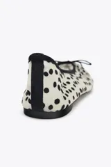 Zapato tipo bailarina de malla color blanco con estampado de lunares negros, detalle de lazo en la puntera, tirador trasero y suela plana.