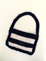 Cartera tejida a crochet con hilo 100% de algodón, con diseño a rayas y volados bordeando la cartera extendiéndose hacia la manija.