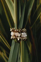 Pack de tres pulseras elásticas con piezas de diferentes formas, tamaños y colores en dorado y blanco.