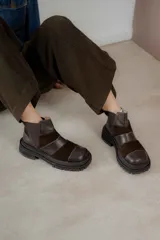 Botas cortas de cuero marrón con punta cuadrada y paneles de cuero liso y gamuza. Presentan elásticos laterales y suela track.