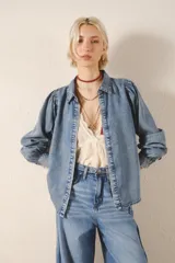 Camisa celeste de tencel, de calce recto, con manga larga amplia con frunces en los hombros y cuello camisero. Mangas terminadas en puño con botón y ojal. Cartera delantera con botones metálicos con el logo de la marca.