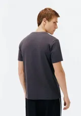 Camiseta blanca de algodón con cuello redondo y mangas cortas. Estampa rectangular con borde negro que contiene la frase "NATURAL ATMOSPHERE" en letras mayúsculas y una imagen de montañas y mar.